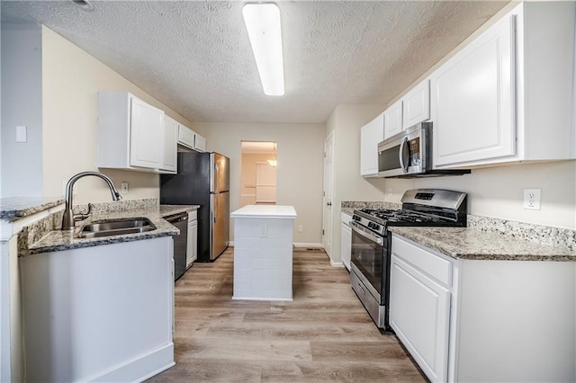 kitchen with sink, light hardwood / wood-style flooring, appliances with stainless steel finishes, white cabinetry, and light stone counters