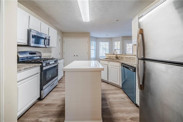 kitchen featuring sink, light wood-type flooring, white cabinets, and appliances with stainless steel finishes