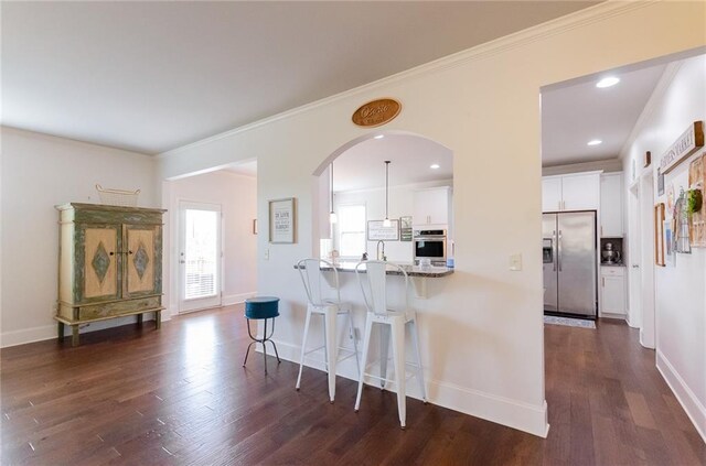 6828 New Fern Ln, Flowery Branch, GA 30542 - kitchen with appliances with stainless steel finishes, a breakfast bar area, white cabinets, dark wood-style floors, and ornamental molding