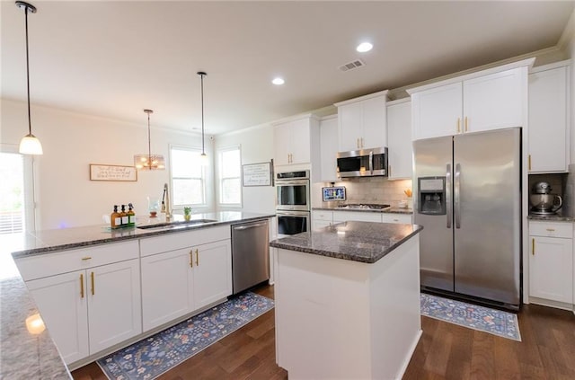 6828 New Fern Ln, Flowery Branch, GA 30542 - kitchen with appliances with stainless steel finishes, a kitchen island, dark wood-style flooring, tasteful backsplash, and white cabinets