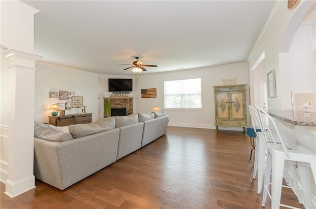 6828 New Fern Ln, Flowery Branch, GA 30542 - living area featuring a ceiling fan, a fireplace, wood finished floors, arched walkways, and crown molding