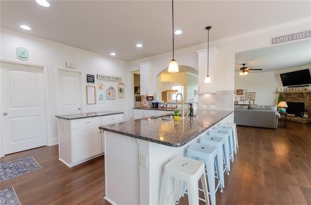 6828 New Fern Ln, Flowery Branch, GA 30542 - kitchen featuring arched walkways, a ceiling fan, dark wood-type flooring, white cabinets, and a peninsula