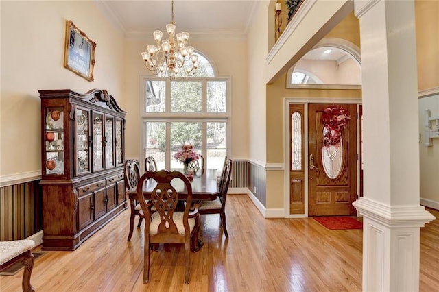 dining space with light wood finished floors, ornamental molding, a chandelier, and wainscoting