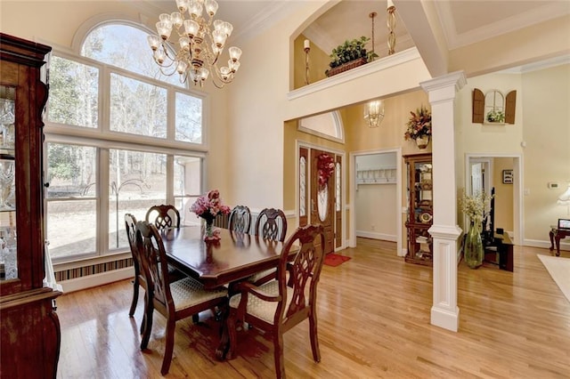 dining room with baseboards, light wood-style floors, ornamental molding, ornate columns, and a chandelier