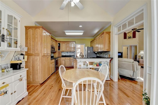 dining area featuring ornamental molding, light wood-type flooring, vaulted ceiling, and ceiling fan