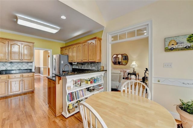 kitchen with light wood finished floors, ornamental molding, freestanding refrigerator, and decorative backsplash