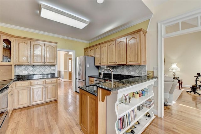 kitchen with dark stone counters, a breakfast bar, crown molding, light wood-style floors, and a sink