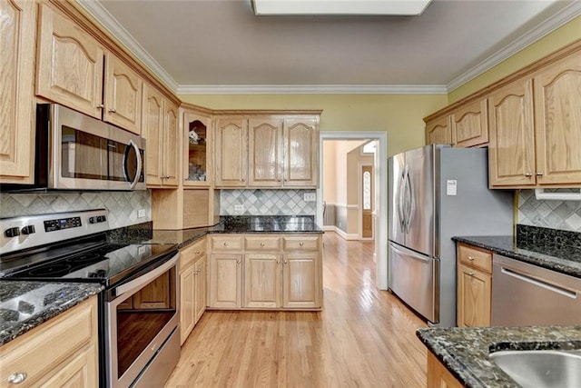 kitchen featuring stainless steel appliances, ornamental molding, and dark stone countertops