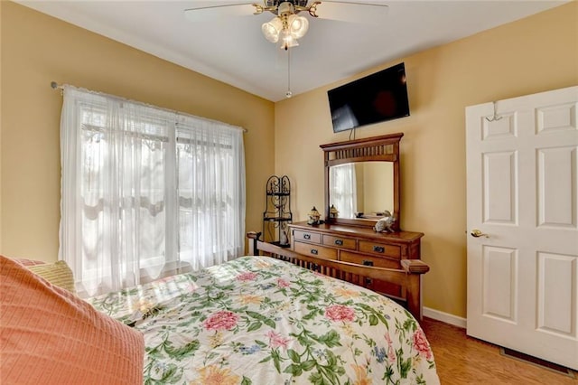 bedroom with light wood-type flooring, baseboards, and a ceiling fan