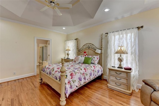 bedroom with light wood-type flooring, multiple windows, and a tray ceiling