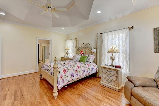 bedroom featuring light wood-type flooring, baseboards, a tray ceiling, and crown molding