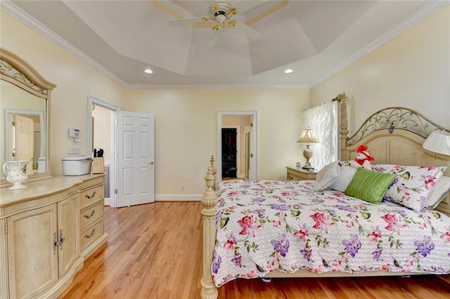 bedroom featuring a raised ceiling, baseboards, crown molding, and light wood finished floors