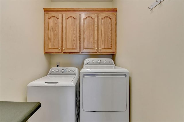 laundry area with separate washer and dryer and cabinet space