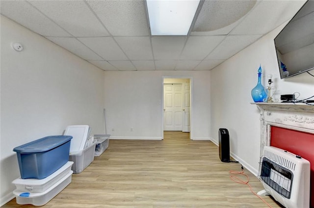 interior space with heating unit, a paneled ceiling, baseboards, and wood finished floors