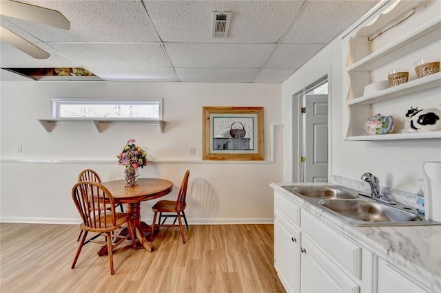 dining room featuring light wood-type flooring, baseboards, visible vents, and a drop ceiling