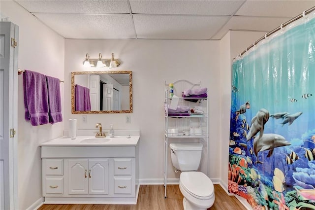 full bath featuring baseboards, a drop ceiling, toilet, wood finished floors, and vanity