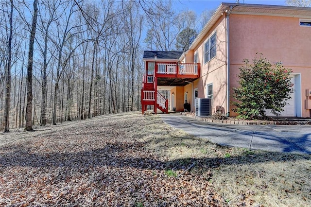 rear view of house featuring stairs, cooling unit, a deck, and stucco siding