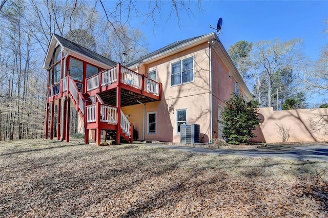 back of property featuring stucco siding, central AC, a wooden deck, and stairs