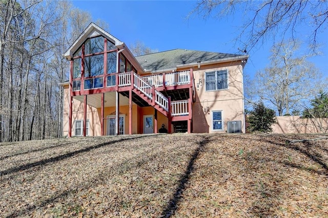 back of house with stucco siding, stairway, a wooden deck, and central AC unit