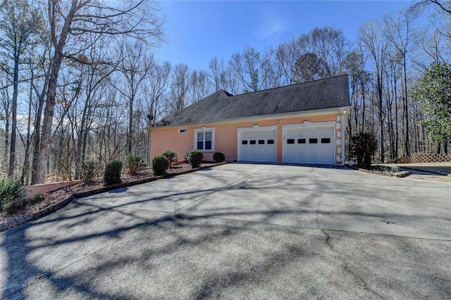 view of property exterior with an attached garage, aphalt driveway, and stucco siding