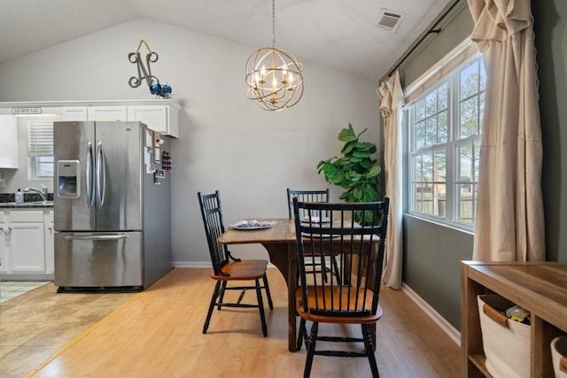 dining space with lofted ceiling, light wood-style flooring, visible vents, and a chandelier