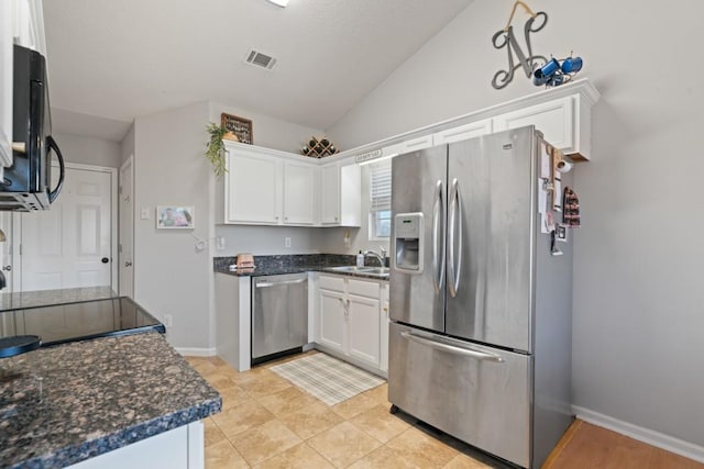 kitchen featuring white cabinets, vaulted ceiling, stainless steel appliances, and a sink