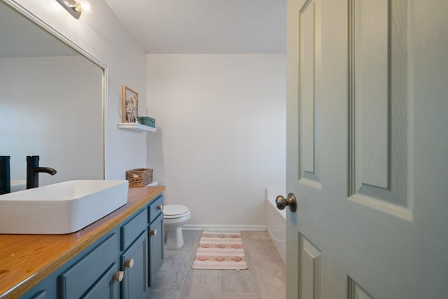 full bathroom featuring baseboards, vanity, toilet, and a tub