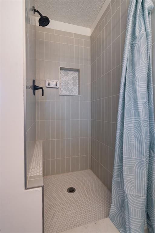 full bath featuring tiled shower and a textured ceiling