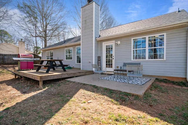 back of house featuring a deck, a chimney, a patio area, and fence