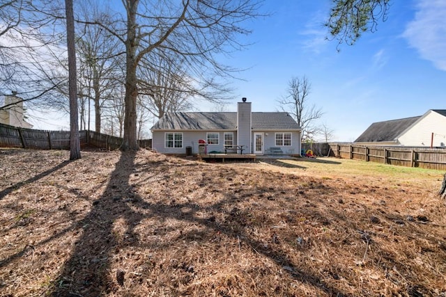 back of property featuring a fenced backyard, a chimney, and a deck