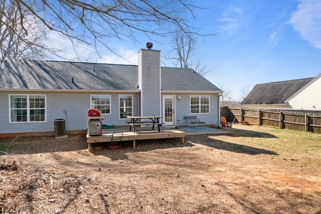 rear view of house with a shingled roof, a chimney, fence, and a wooden deck