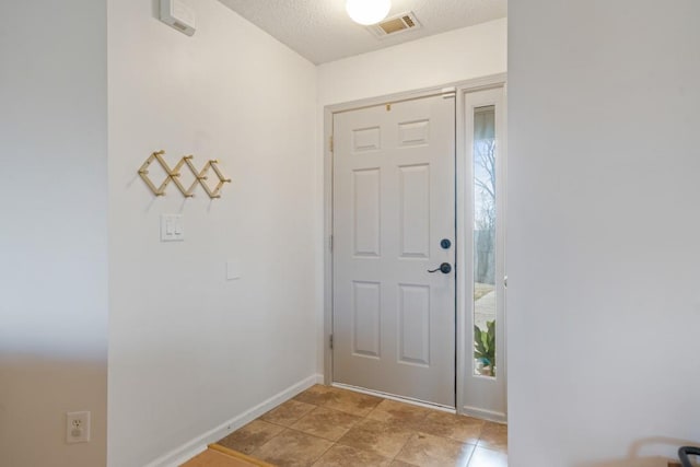 entrance foyer featuring baseboards, visible vents, and a textured ceiling