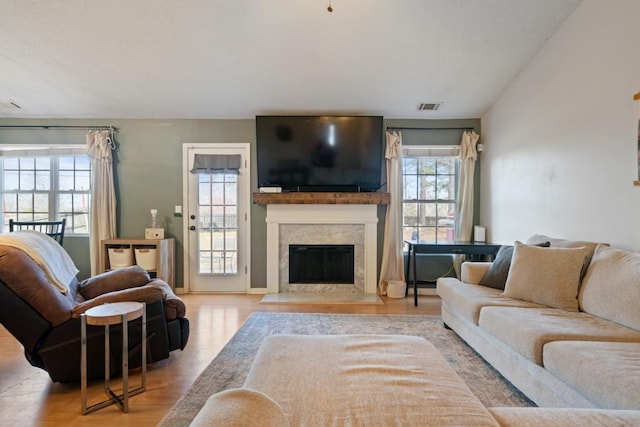 living room featuring lofted ceiling, a fireplace, visible vents, and wood finished floors