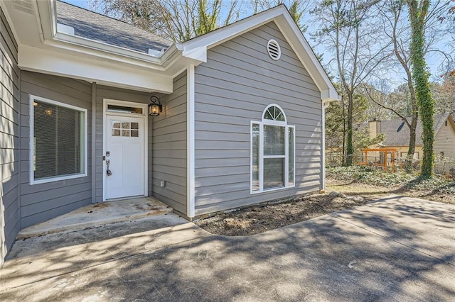 view of exterior entry with roof with shingles