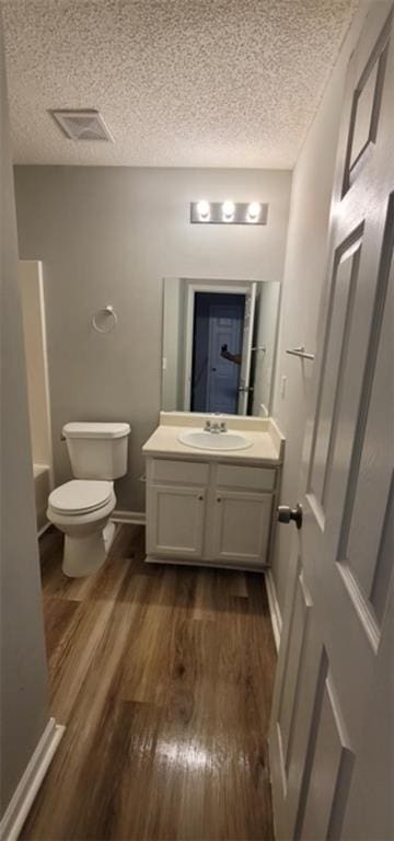 bathroom with hardwood / wood-style floors, vanity, a tub to relax in, and toilet