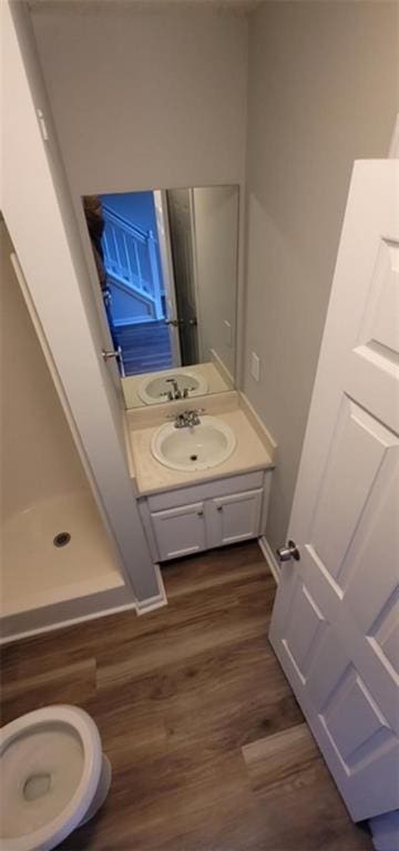 bathroom featuring a shower, toilet, vanity, and hardwood / wood-style flooring