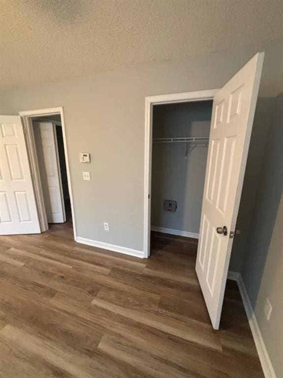 unfurnished bedroom with dark hardwood / wood-style floors, a textured ceiling, and a closet