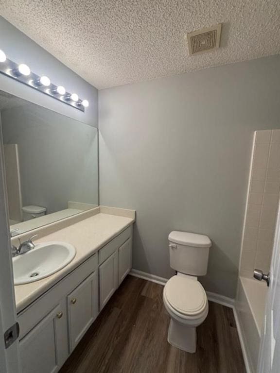 full bathroom featuring vanity, toilet, wood-type flooring, and a textured ceiling