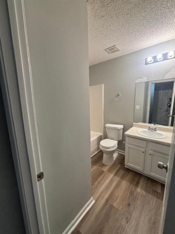 bathroom with vanity, wood-type flooring, a textured ceiling, and toilet