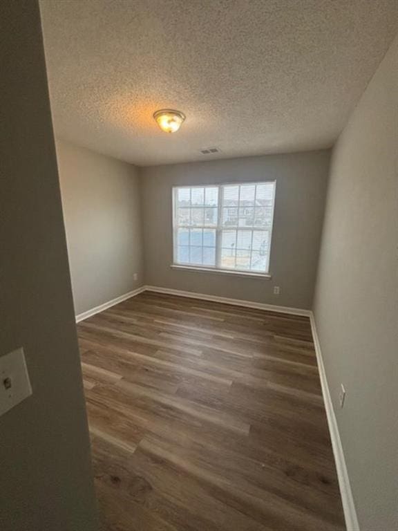 unfurnished room with dark hardwood / wood-style flooring and a textured ceiling