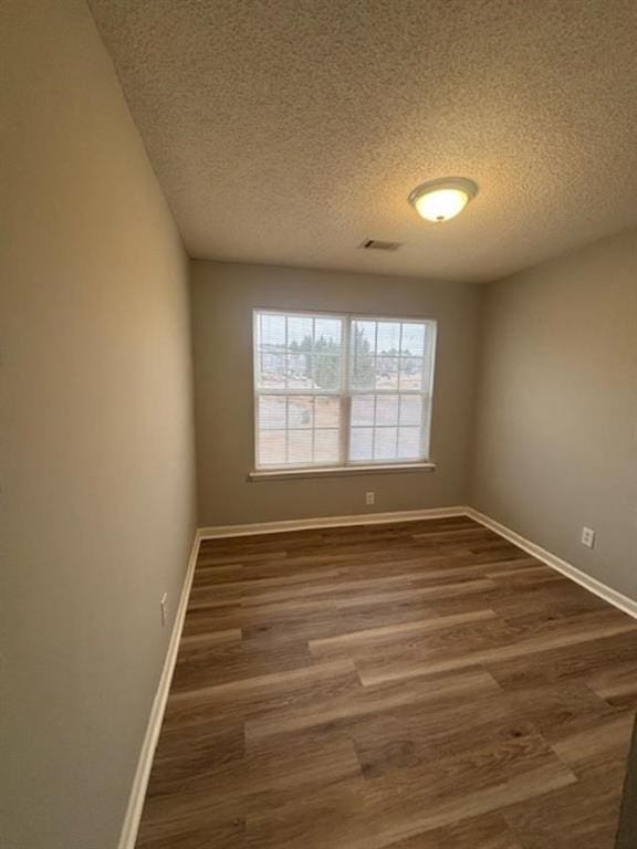 empty room with a textured ceiling and dark wood-type flooring