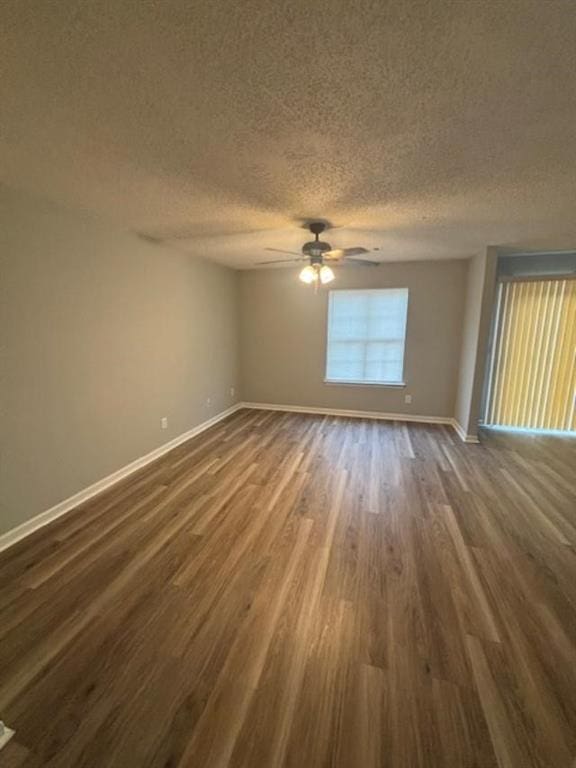 empty room with ceiling fan, dark hardwood / wood-style flooring, and a textured ceiling