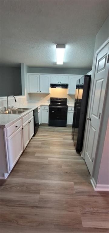 kitchen featuring black appliances, white cabinets, sink, a textured ceiling, and light hardwood / wood-style floors