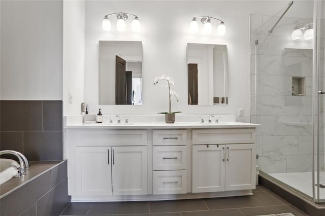 bathroom with tiled tub, a sink, a shower stall, and double vanity