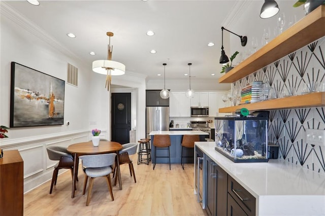 kitchen featuring visible vents, appliances with stainless steel finishes, ornamental molding, light countertops, and open shelves