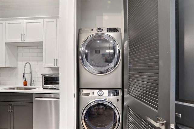 laundry area with a sink, laundry area, a toaster, and stacked washer / dryer