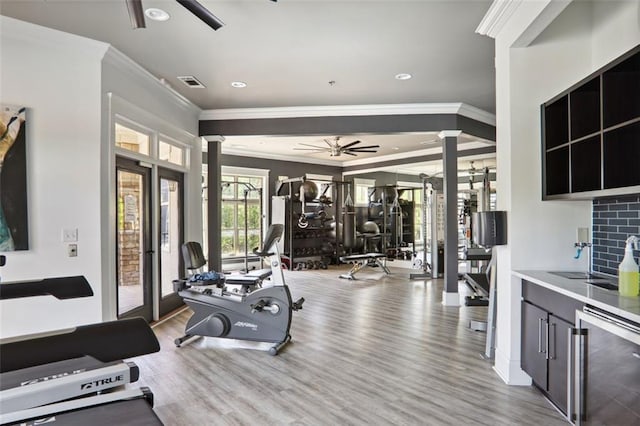 exercise room with visible vents, a ceiling fan, ornamental molding, wood finished floors, and beverage cooler