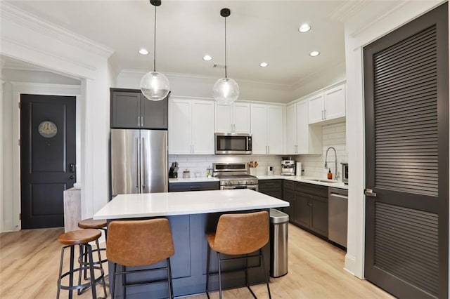 kitchen featuring stainless steel appliances, a sink, white cabinetry, light countertops, and crown molding