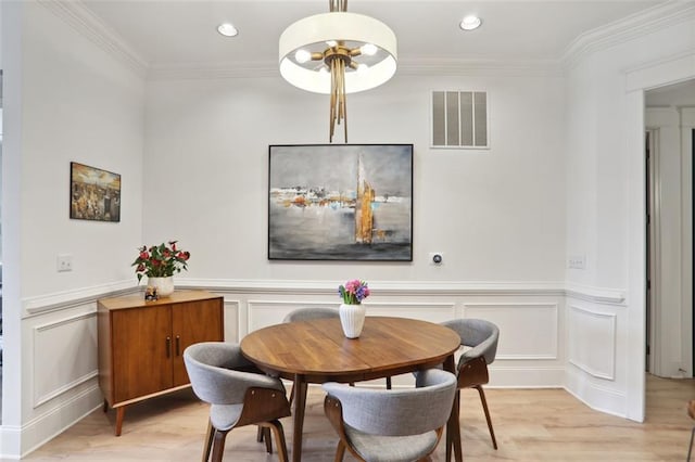 dining room with a decorative wall, recessed lighting, visible vents, ornamental molding, and light wood-type flooring