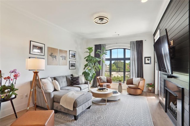 living room with a large fireplace, baseboards, light wood-style floors, and crown molding